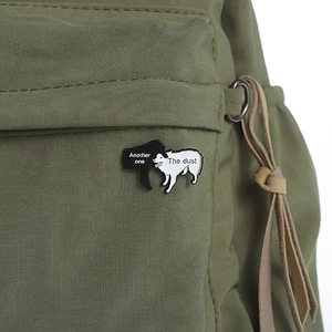 Detail of funny black and white dog enamel brooch on green canvas backpack with text