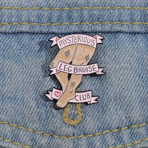 Broche en émail Mysterious Leg Bruise Club avec ruban rose sur tissu denim bleu