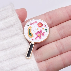 Spilla smaltata creativa a forma di lente d'ingrandimento con microbi colorati su maglione