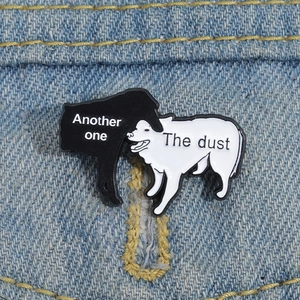 Macro shot of cartoon black and white dog enamel pins on blue denim fabric background