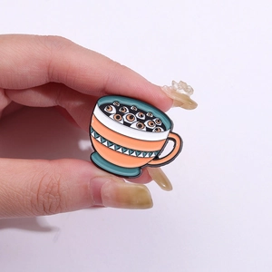 Creative coffee cup enamel pin with eyeball patterns and orange geometric design
