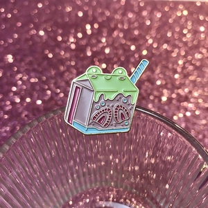 Detalle de pin esmaltado con diseño de cartón de leche de rana sobre vidrio texturizado