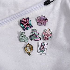 Set of seven witchy enamel pins featuring skulls, tarot cards, and mystical elements on canvas