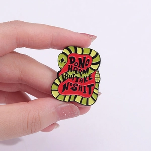 Macro view of green snake enamel pin featuring DO NO HARM BUT TAKE NO SHIT text