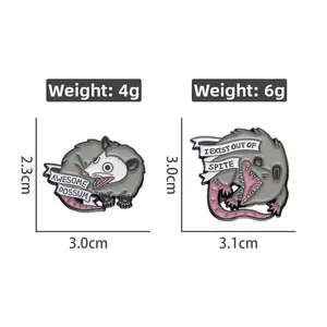 Detail view of two cartoon opossum enamel pins with funny slogans and dimensions