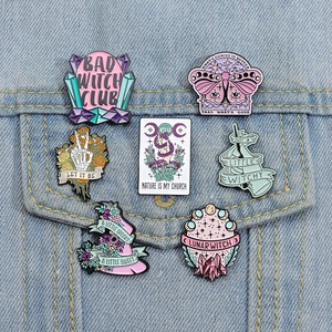 Set of 7 pastel witchy enamel pins with skull, moth and moon motifs on denim jacket