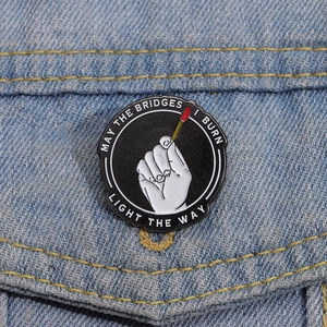 Detail of circular enamel badge with matchstick design pinned on blue denim jacket
