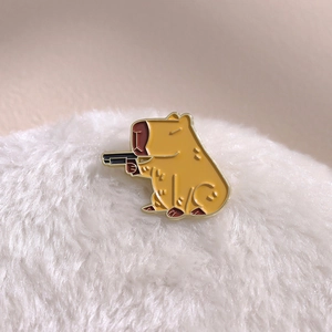 Spilla smaltata capibara con pistola su fondo di peluche per abbigliamento e borse