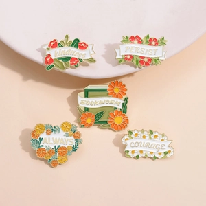 Set of five floral enamel pins including daisy, book and leaves on a ceramic plate