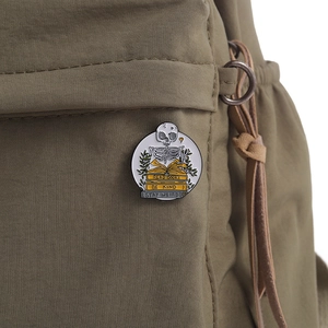 Detail of skeleton reading books enamel pin on green canvas backpack texture