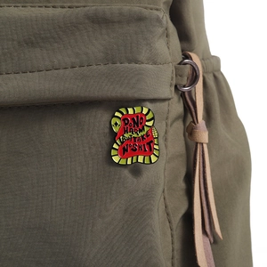 Detail of snake enamel pin with text on green backpack for bag decoration