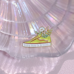Creative yellow sneaker enamel pin with floral details and every step is growth text