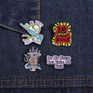 Detailed macro view of four enamel pins with medical and snake designs on denim fabric