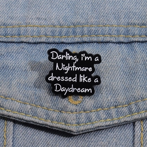 Broche en émail avec citation Darling I'm a Nightmare sur une veste en denim