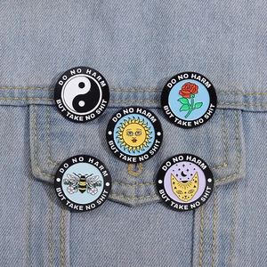 Set of five round enamel pins featuring various symbols on a light blue denim jacket