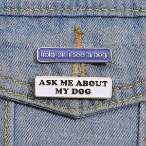 Detail of dog themed enamel pins on denim jacket featuring Hold On I See A Dog text