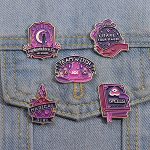 Detailed view of magic themed enamel pins featuring moon cat and witch hat on denim jacket