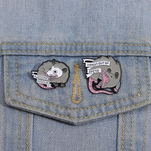Detail of funny opossum enamel pins on denim jacket showing awesome possum and spite text