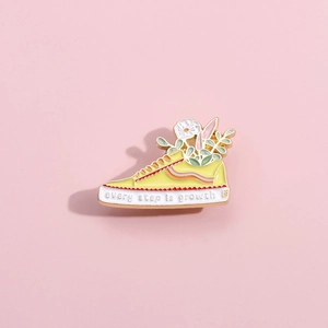 Yellow skateboard shoe enamel pin with blooming flowers and Every Step is Growth text