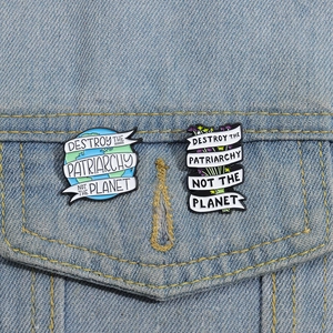 Detailopname van emaille pins met slogans op de zak van een blauw spijkerjasje