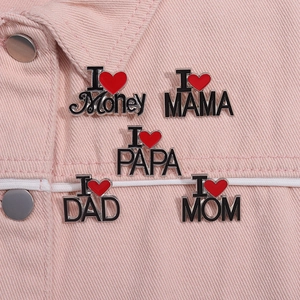 Dettaglio di spille smaltate I Love Mom su giacca di jeans rosa e artigianato