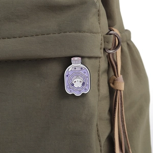Detail of cute purple bunny potion bottle enamel pin on an olive canvas bag surface