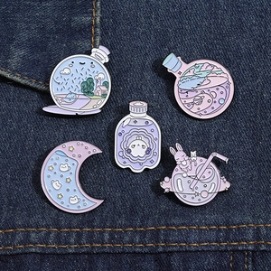 Flat lay of macaron-colored cartoon enamel pins with bottle and moon motifs on denim