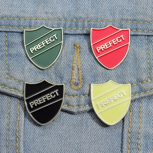 Detail of shield-shaped PREFECT enamel pins on denim pocket in four color options