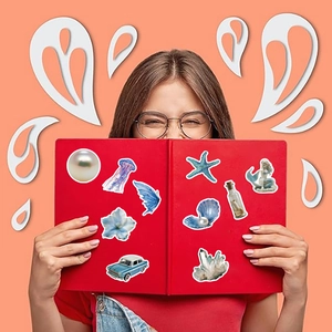 Dettaglio di adesivi oceano blu su copertina di libro rossa con meduse e conchiglie