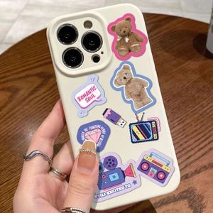 Creamy white Y2K cartoon phone case with teddy bear stickers held by hand on wooden desk