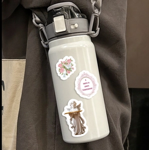 Detail of white water bottle with retro floral stickers and a gray carrying strap