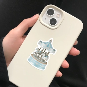 Close-up of cream iPhone case with blue carousel sticker design held by hand