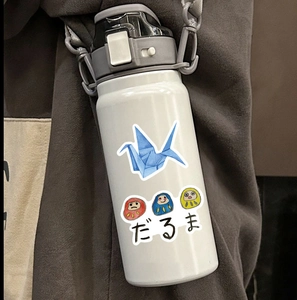 Détail de gourde blanche avec autocollants japonais et bandoulière réglable