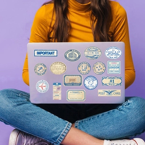 Detail of retro travel stickers with vintage postal stamps on a purple laptop