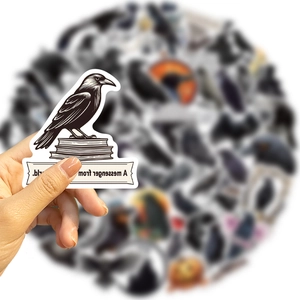 Detail of hand holding a black crow sticker with book graphics for DIY decoration