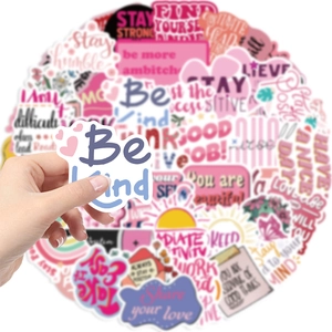 Close-up of pink inspirational quote stickers for laptops and guitars held by hand