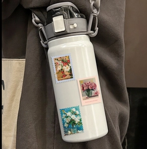 Détail de stickers timbres floraux sur gourde isotherme blanche avec sangle grise