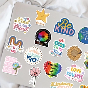 Close-up of Be Kind vinyl stickers applied on a laptop with floral and rainbow designs