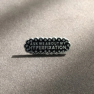 Enamel brooch with Ask Me About My Hyperfixation text and silver scalloped edges