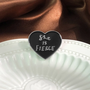 Black heart enamel brooch with She Is Fierce silver text on elegant silk background