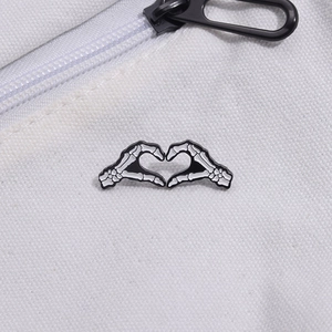 Badge épinglette en émail mains squelette cœur sur sac toile avec finition noir et blanc