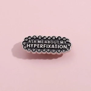 Vintage black enamel pin with ASK ME ABOUT MY HYPERFIXATION quote and silver metal edge