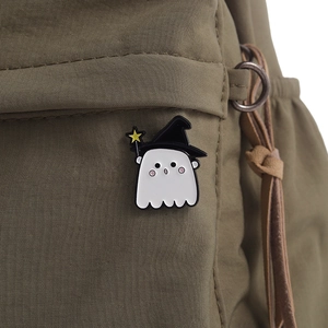 Detail of cute ghost enamel pin with wizard hat and star wand on canvas bag