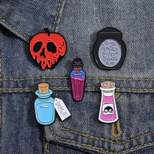 Close-up of five gothic magic potion enamel pins on a dark blue denim jacket pocket