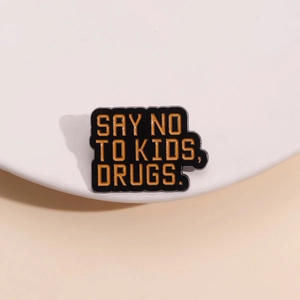 Funny enamel pin with Say No To Kids Drugs quote on black background displayed on a stand