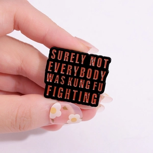 Retro black enamel pin with orange Kung Fu text displayed on a light background