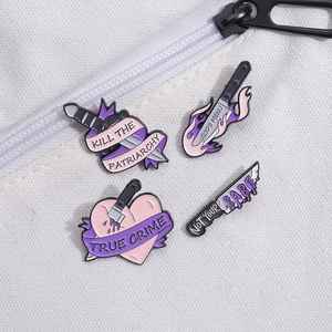 Set di quattro spille in smalto viola con cuore, pugnale e slogan su tela bianca