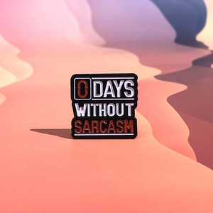Enamel pin with '0 DAYS WITHOUT SARCASM' text in minimalist black, white, and red
