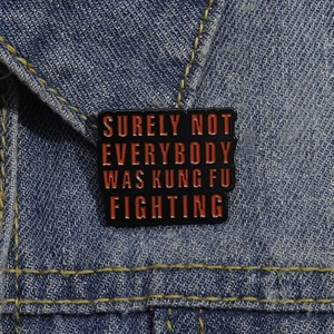 Close-up of a red and black Kung Fu Fighting enamel pin on a denim jacket collar