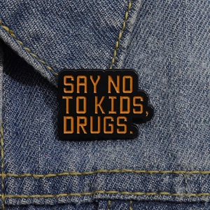 Say No To Kids Drugs enamel pin brooch in black and orange on denim jacket